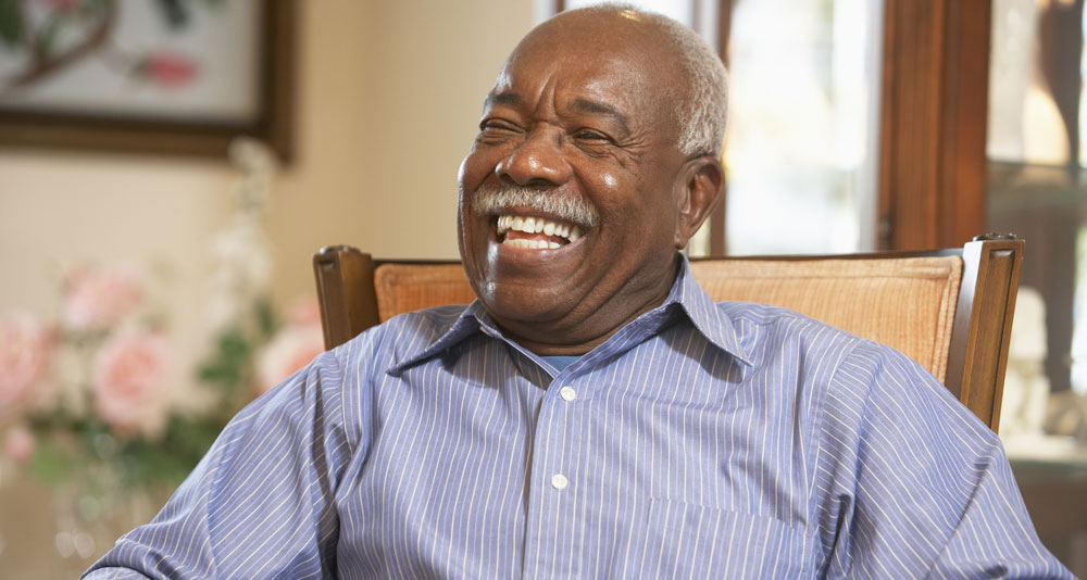 Happy Senior Man sitting in armchair grinning