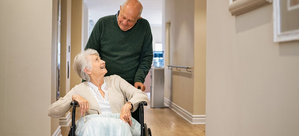VRS seniors communities senior man visiting disabled woman on wheelchair at nursing home