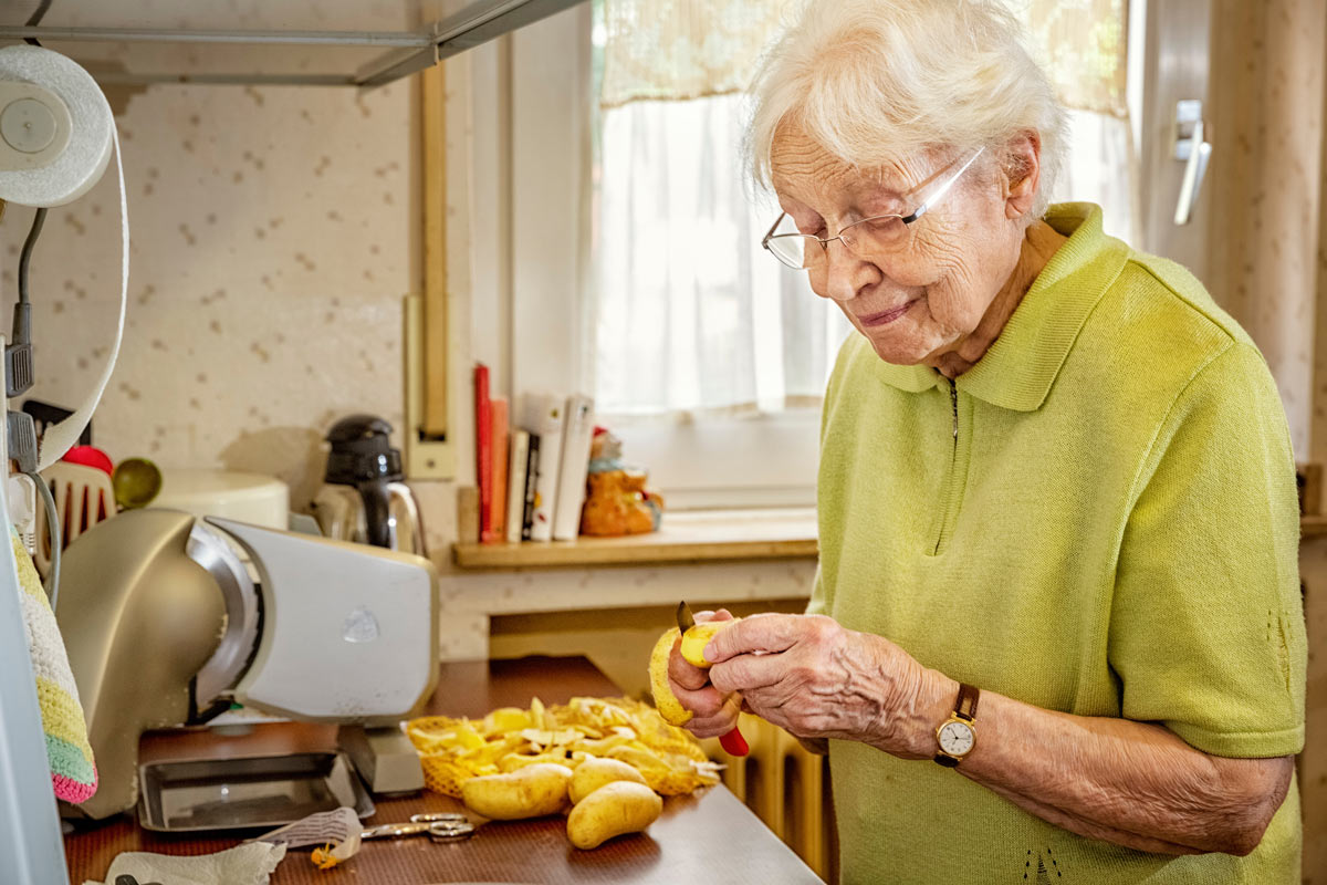 VRS communities senior peeling potatoes for cooking in assisted living suite